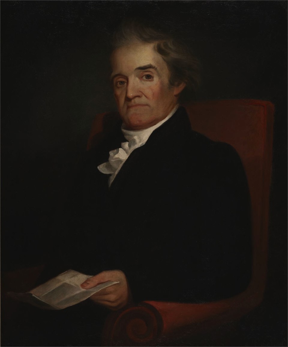 十九世紀的油畫肖像：年長的 Noah Webster 坐在紅色扶手椅上，穿深色外套、白色領巾，手上拿著一張紙，背景深暗